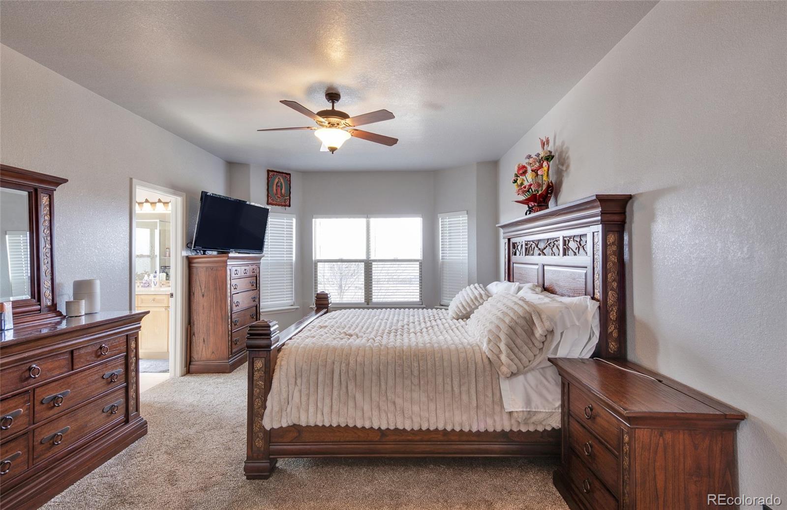 271 Corvette Circle Fort Lupton, CO 80621 - Photo 9 of 39 a bedroom with a bed dresser and a flat tv screen