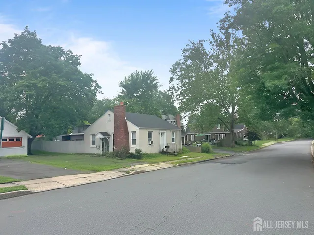 a view of a house with a big yard and large trees