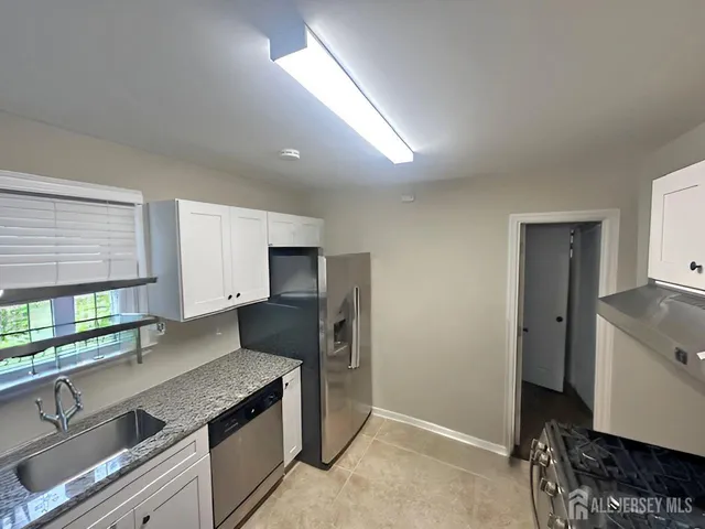 a kitchen with stainless steel appliances granite countertop a sink a stove and a refrigerator