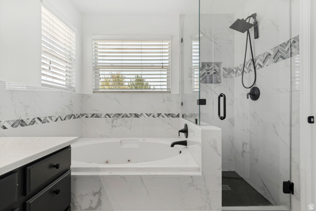 4752 South 4075th Street West Roy, UT 84067 - Photo 12 of 28 Freestanding tub with white tile surround, glass-enclosed shower with matte black fixtures, and a vanity with a light-colored countertop