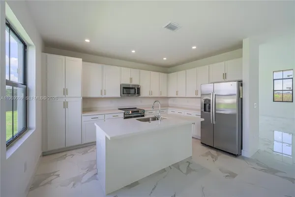a kitchen with stainless steel appliances granite countertop a refrigerator sink and stove