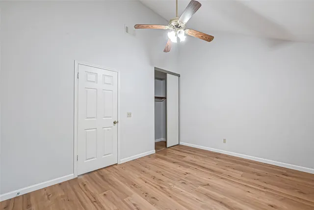 an empty room with wooden floor fan and window