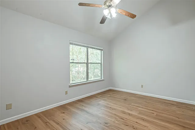 an empty room with wooden floor chandelier fan and window