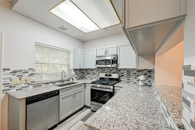 a kitchen with stainless steel appliances granite countertop a sink stove and refrigerator
