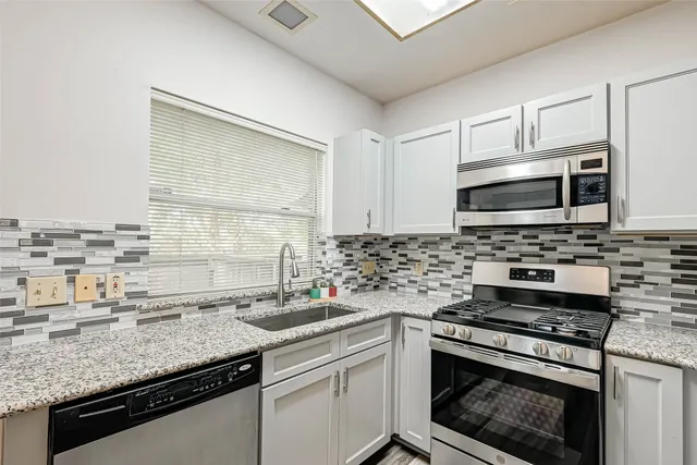 a kitchen with stainless steel appliances granite countertop a sink stove and microwave