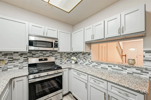 a kitchen with granite countertop white cabinets stainless steel appliances and a sink