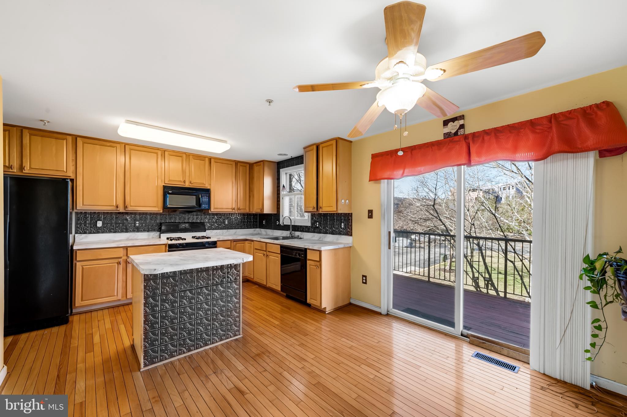 252 Robert Street Baltimore, MD 21217 - Photo 13 of 51 a kitchen with stainless steel appliances kitchen island granite countertop a refrigerator a stove top oven a chimney wooden floor and cabinets