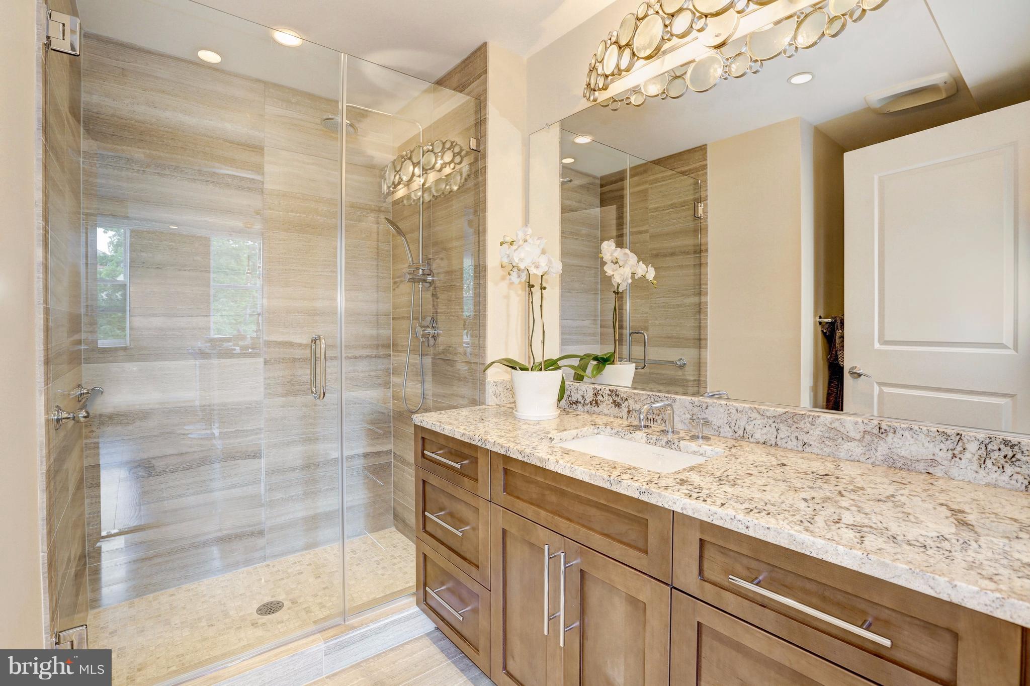 3052 R Street Northwest, Unit 301 Washington, DC 20007 - Photo 14 of 30 a bathroom with a granite countertop sink a mirror and shower