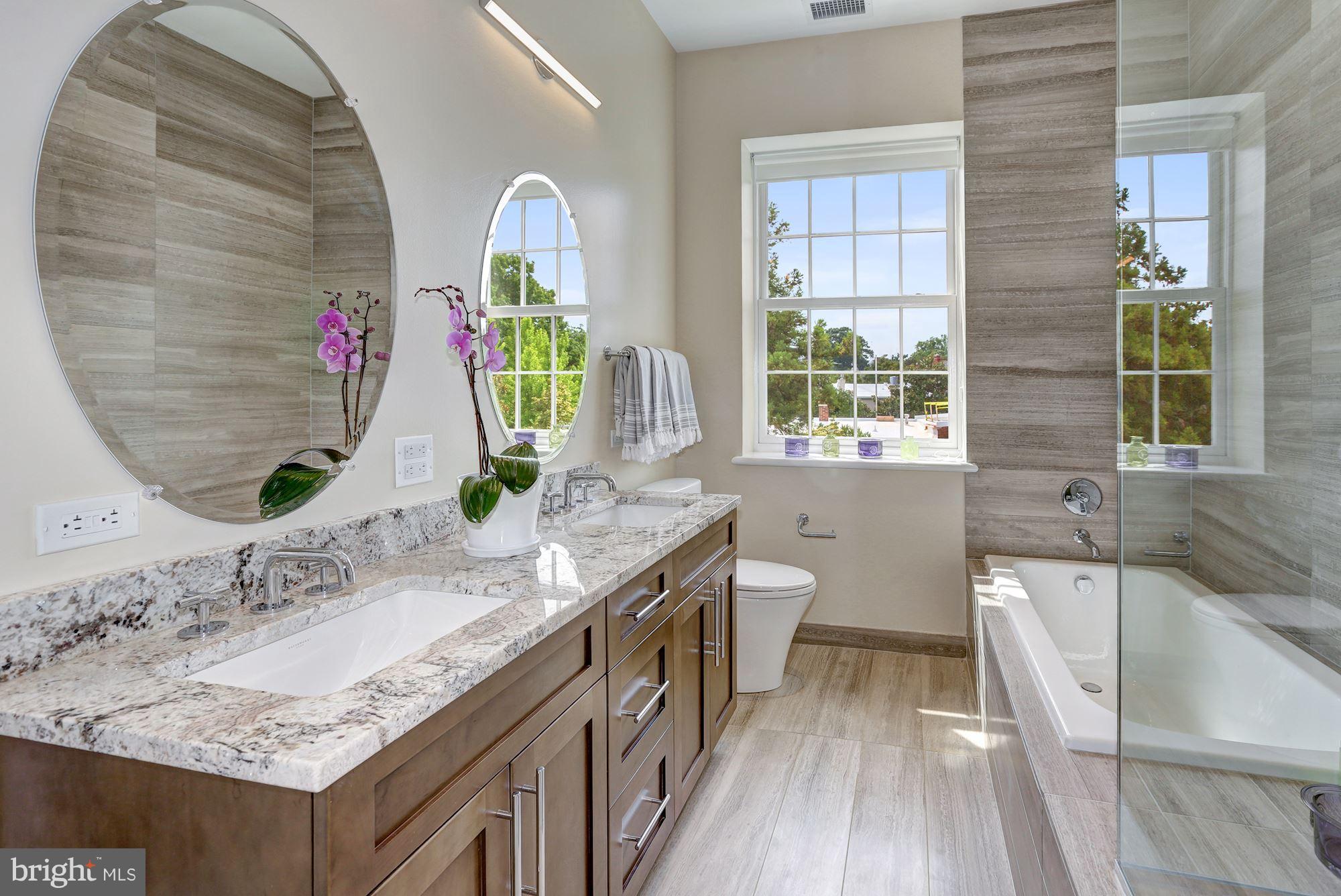 3052 R Street Northwest, Unit 301 Washington, DC 20007 - Photo 21 of 30 a bathroom with a granite countertop tub a sink and a large mirror