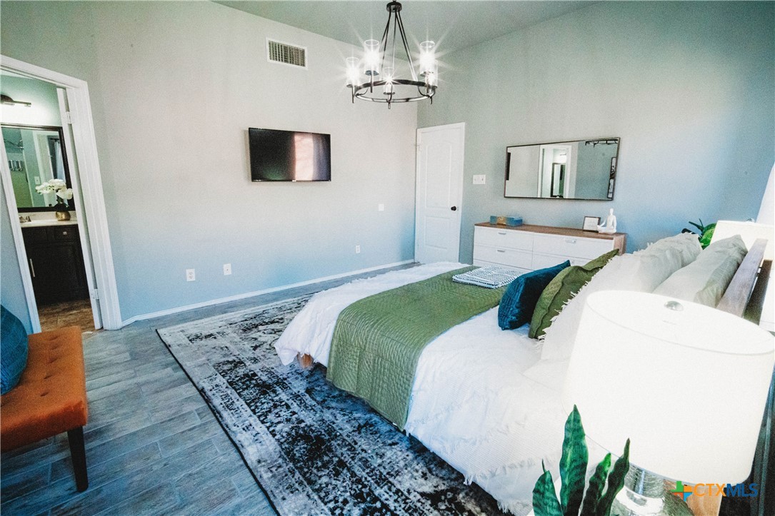 2607 Rampart Loop Killeen, TX 76542 - Photo 19 of 34 a bedroom with a bed and a chandelier
