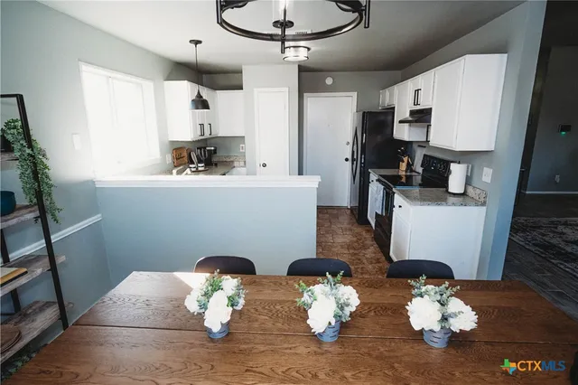 a dining room with furniture a chandelier and kitchen view