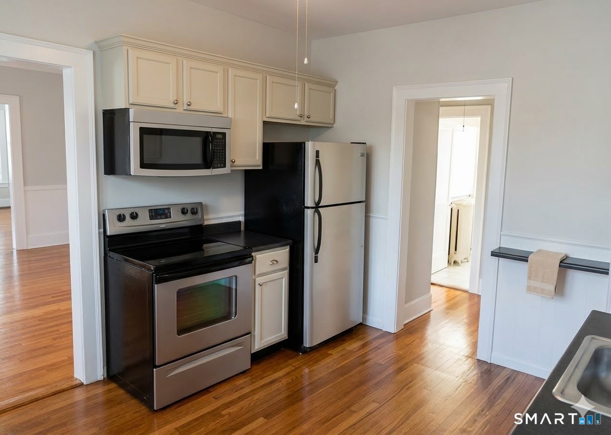 65 Burr Street West Hartford, CT 06107 - Photo 4 of 11 a kitchen with white cabinets stainless steel appliances and wooden floor
