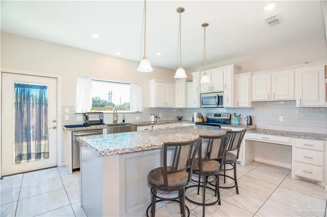 a large kitchen with kitchen island granite countertop a stove a sink dishwasher and a wooden cabinets