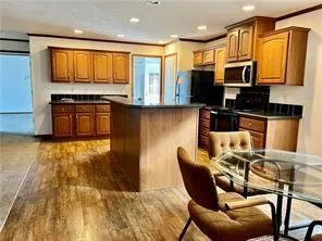 a kitchen with stainless steel appliances granite countertop a stove top oven a sink dishwasher a dining table and chairs with wooden floor