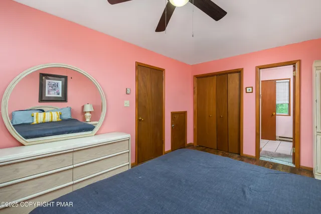 a bedroom with a bed and dresser with wooden floor