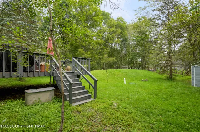 a view of a white house with a big yard and potted plants and large trees