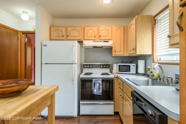 a kitchen with stainless steel appliances granite countertop a refrigerator a sink dishwasher a stove and white countertops with wooden floor