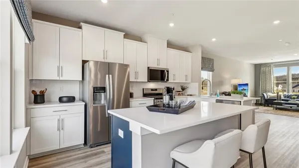 a kitchen with stainless steel appliances a sink a stove a refrigerator cabinets and chairs