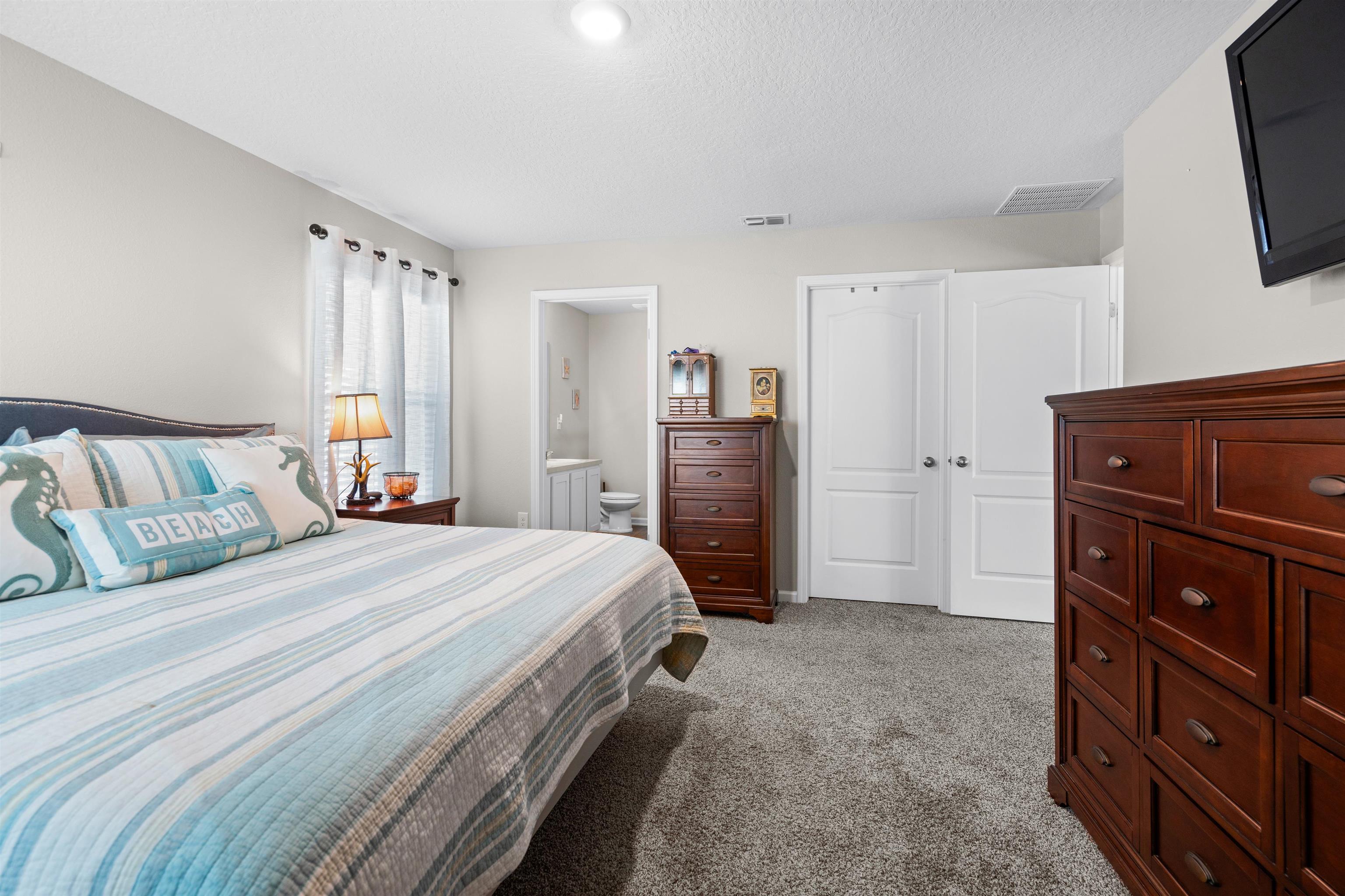 408 Falcon Ridge Road St. Augustine, FL 32084 - Photo 17 of 26 a bedroom with a bed and a flat tv screen on dresser