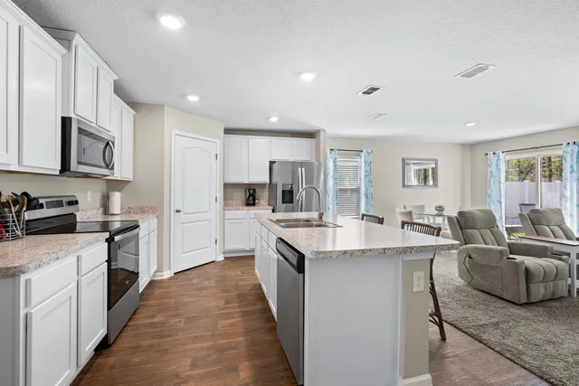 a large kitchen with stainless steel appliances lots of white cabinets