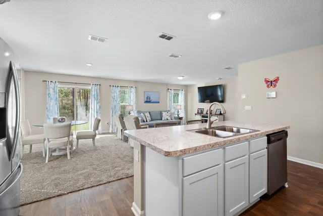 a living room with furniture a flat screen tv and a refrigerator