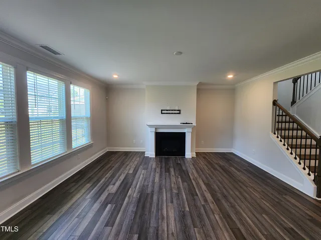 a view of an empty room with wooden floor fireplace and a window