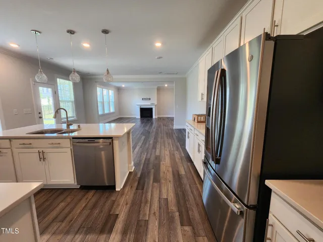 a kitchen with sink a refrigerator and white cabinets