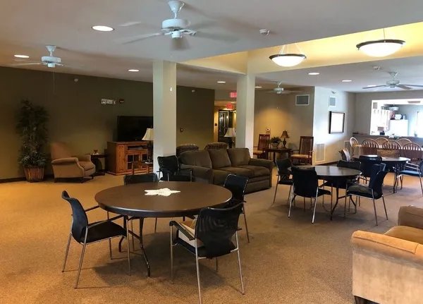 a dining hall with stainless steel appliances a dining table and chairs with a bookshelf