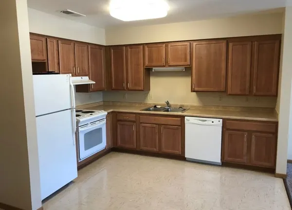 a kitchen with granite countertop a refrigerator stove top oven and cabinets