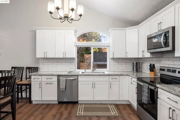 a kitchen with stainless steel appliances granite countertop a stove a sink and a microwave