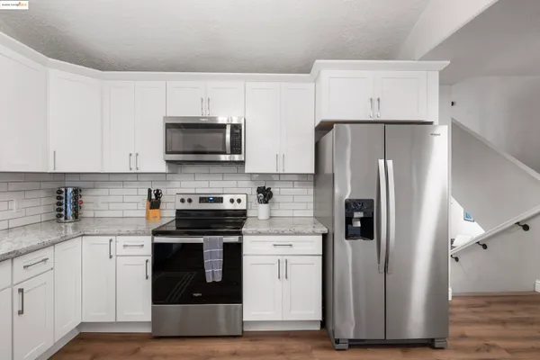 a kitchen with cabinets stainless steel appliances and wooden floor