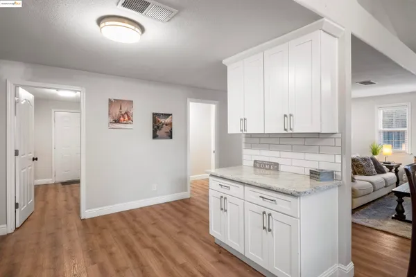 a kitchen with granite countertop a sink cabinets and wooden floor