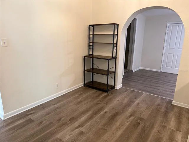 an empty room with wooden floor closet and windows