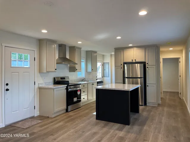 a large kitchen with stainless steel appliances granite countertop a stove a sink dishwasher and a refrigerator with wooden floor