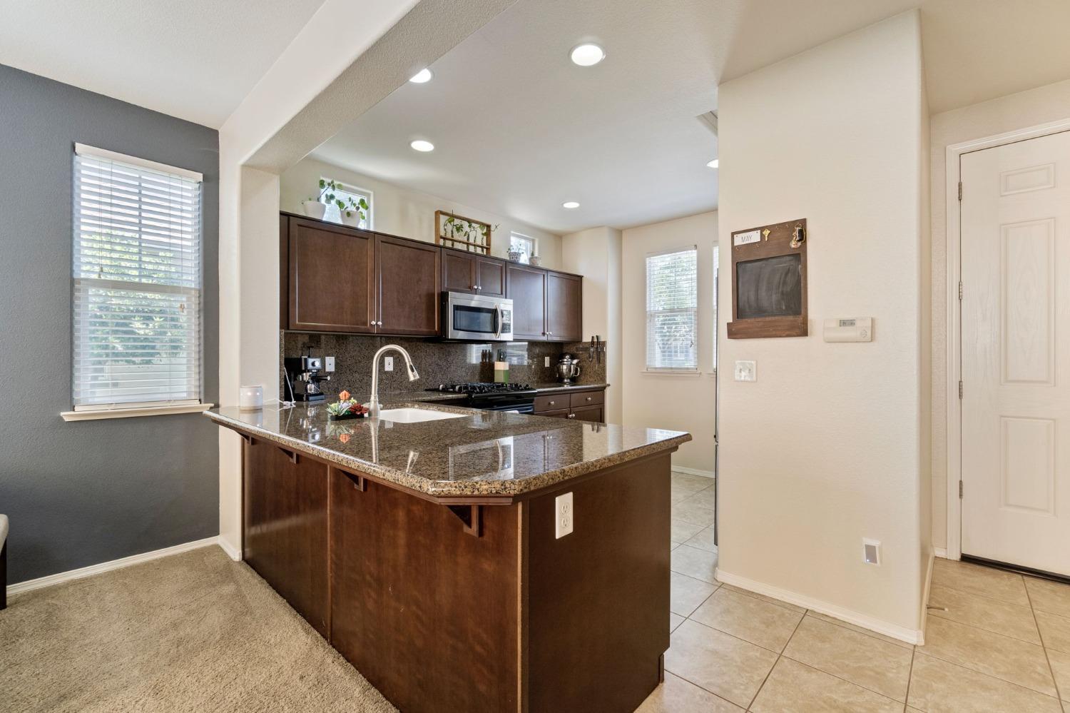 3915 Harlan Ranch Boulevard Clovis, CA 93619 - Photo 13 of 27 a kitchen with kitchen island granite countertop a sink stove top oven and refrigerator