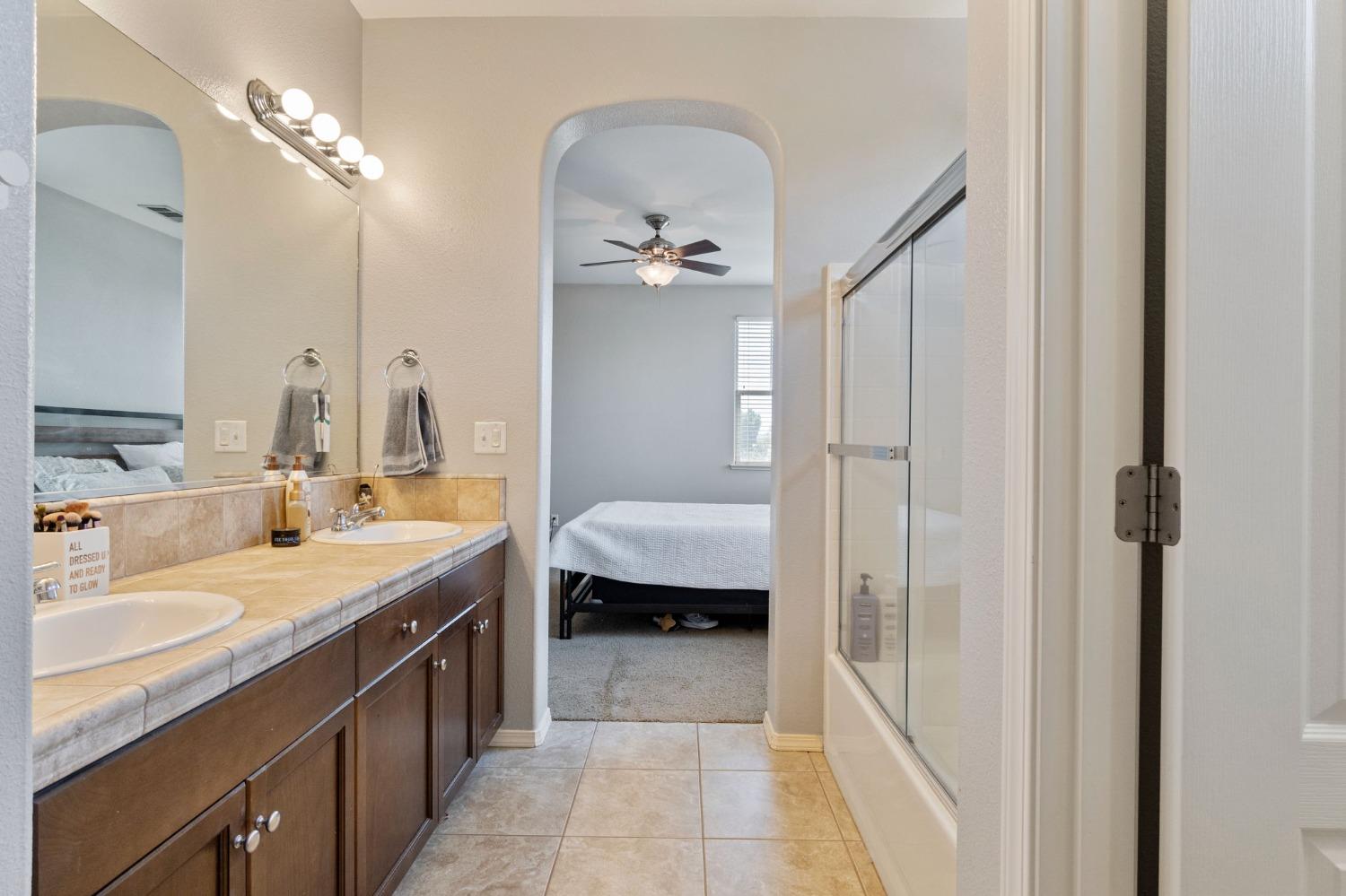 3915 Harlan Ranch Boulevard Clovis, CA 93619 - Photo 24 of 27 a en suite bathroom with a granite countertop sink a toilet a mirror and shower