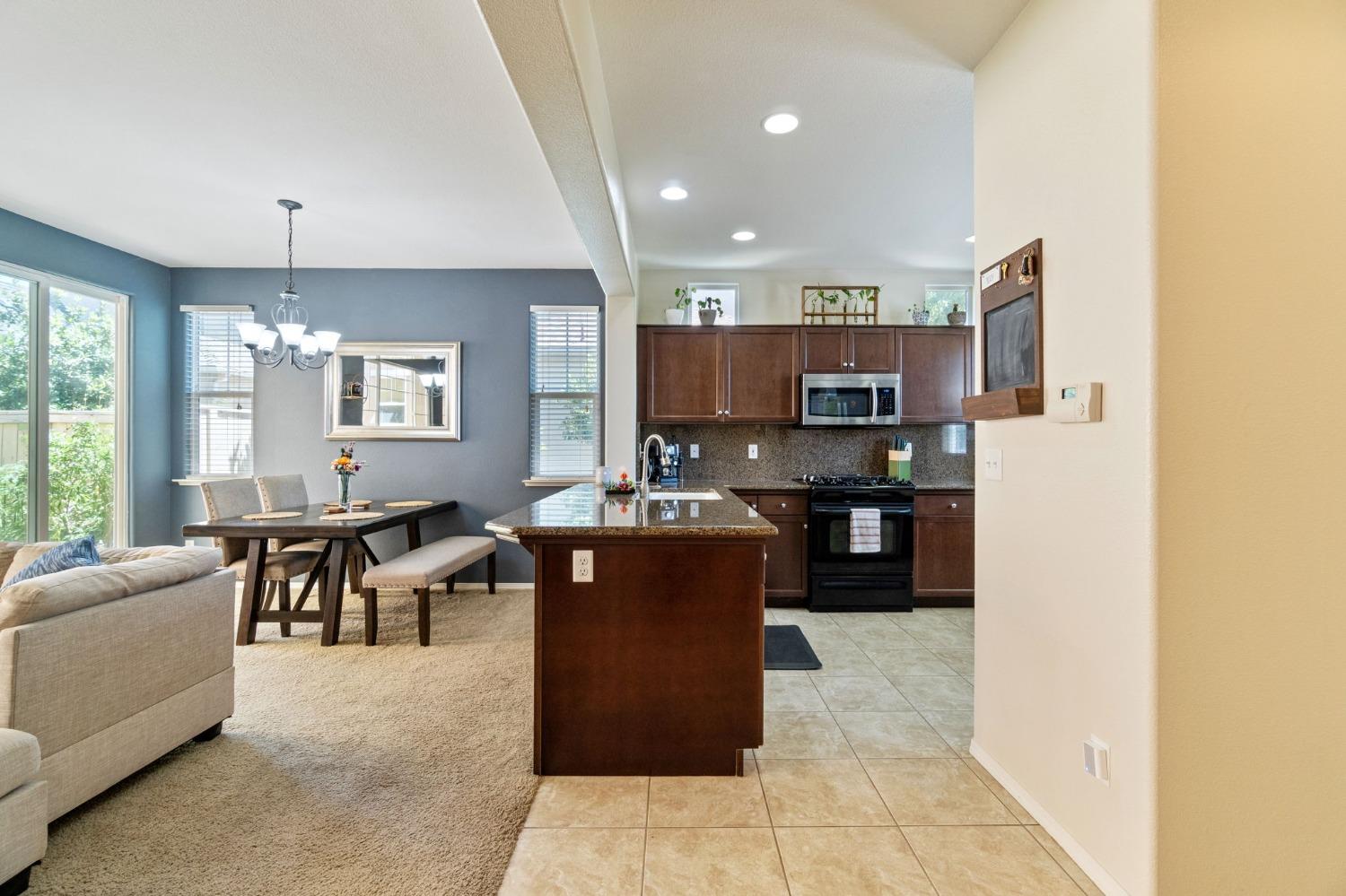 3915 Harlan Ranch Boulevard Clovis, CA 93619 - Photo 9 of 27 a open kitchen with kitchen island granite countertop a refrigerator dining table and chairs