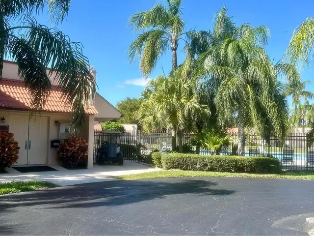 a view of a house with a yard and palm trees
