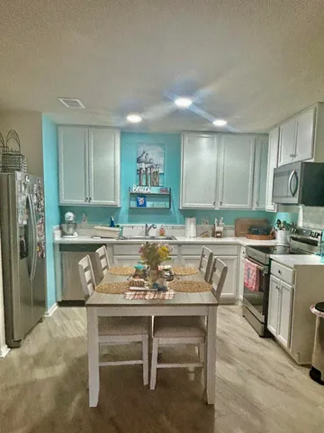 a kitchen with a table chairs refrigerator and microwave