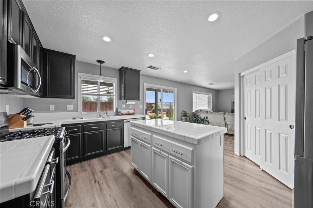 29266 Granite Ridge Court Menifee, CA 92587 - Photo 14 of 51 a large kitchen with stainless steel appliances granite countertop lots of counter top space and wooden floor