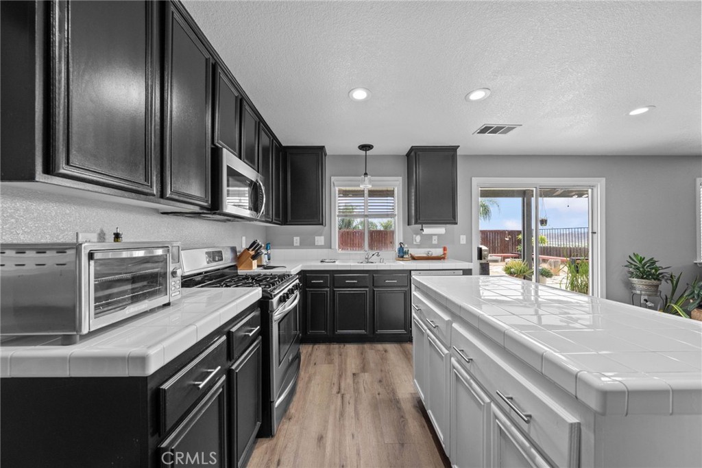 29266 Granite Ridge Court Menifee, CA 92587 - Photo 15 of 51 a kitchen with stainless steel appliances granite countertop a stove top oven a sink dishwasher a refrigerator and cabinets with wooden floor
