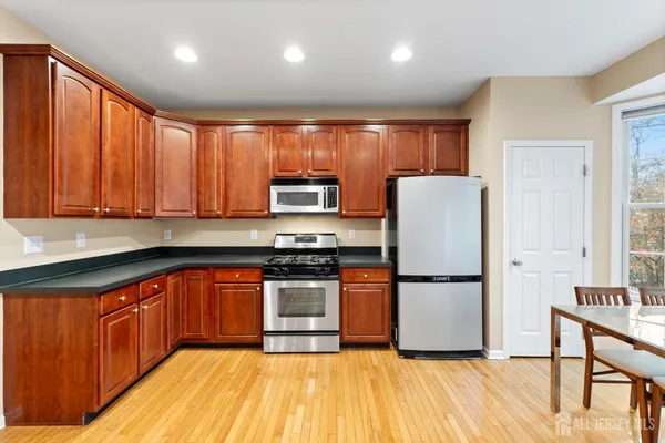 a kitchen with stainless steel appliances granite countertop wooden cabinets a sink and dishwasher a stove with wooden floor