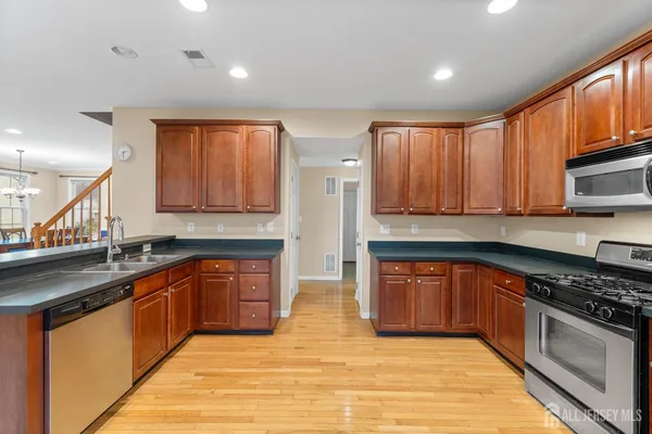 a kitchen with stainless steel appliances granite countertop wooden cabinets a sink and dishwasher with wooden floor