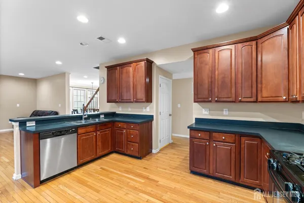 a kitchen with stainless steel appliances granite countertop a stove top oven a sink a dining table and chairs with wooden floor