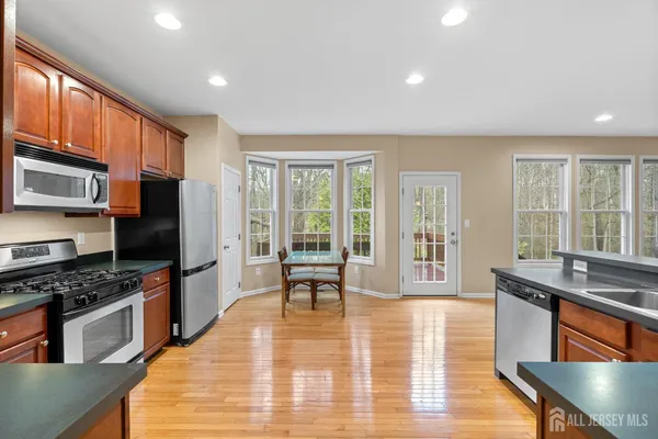 a kitchen with stainless steel appliances granite countertop a stove top oven a sink dishwasher a dining table and chairs with wooden floor