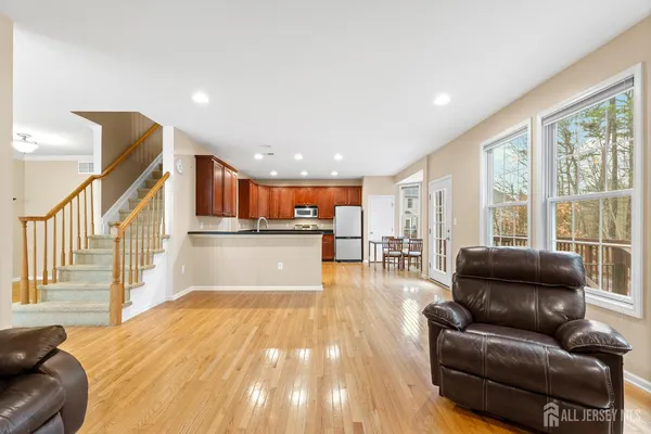 a kitchen with stainless steel appliances kitchen island granite countertop a stove a refrigerator a sink a dining table and chairs with wooden floor
