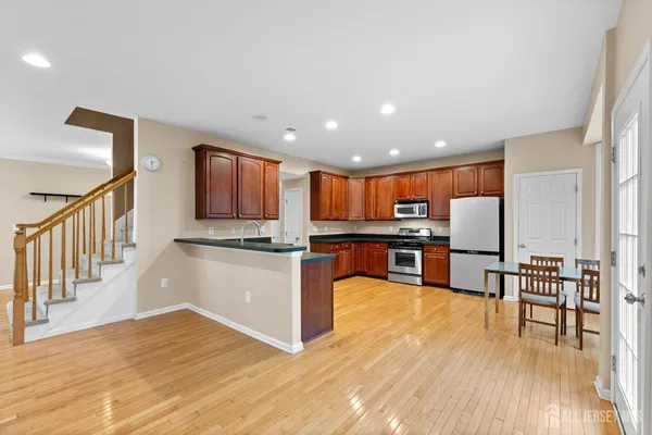 a kitchen with stainless steel appliances granite countertop a refrigerator a sink dishwasher a stove with wooden cabinets and floors