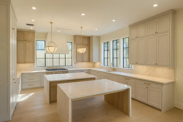 a large kitchen with kitchen island a sink a stove a refrigerator and white cabinets