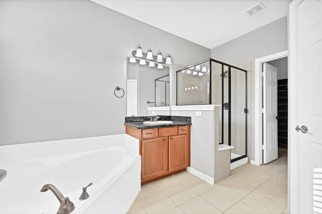 a spacious bathroom with a tub sink and mirror