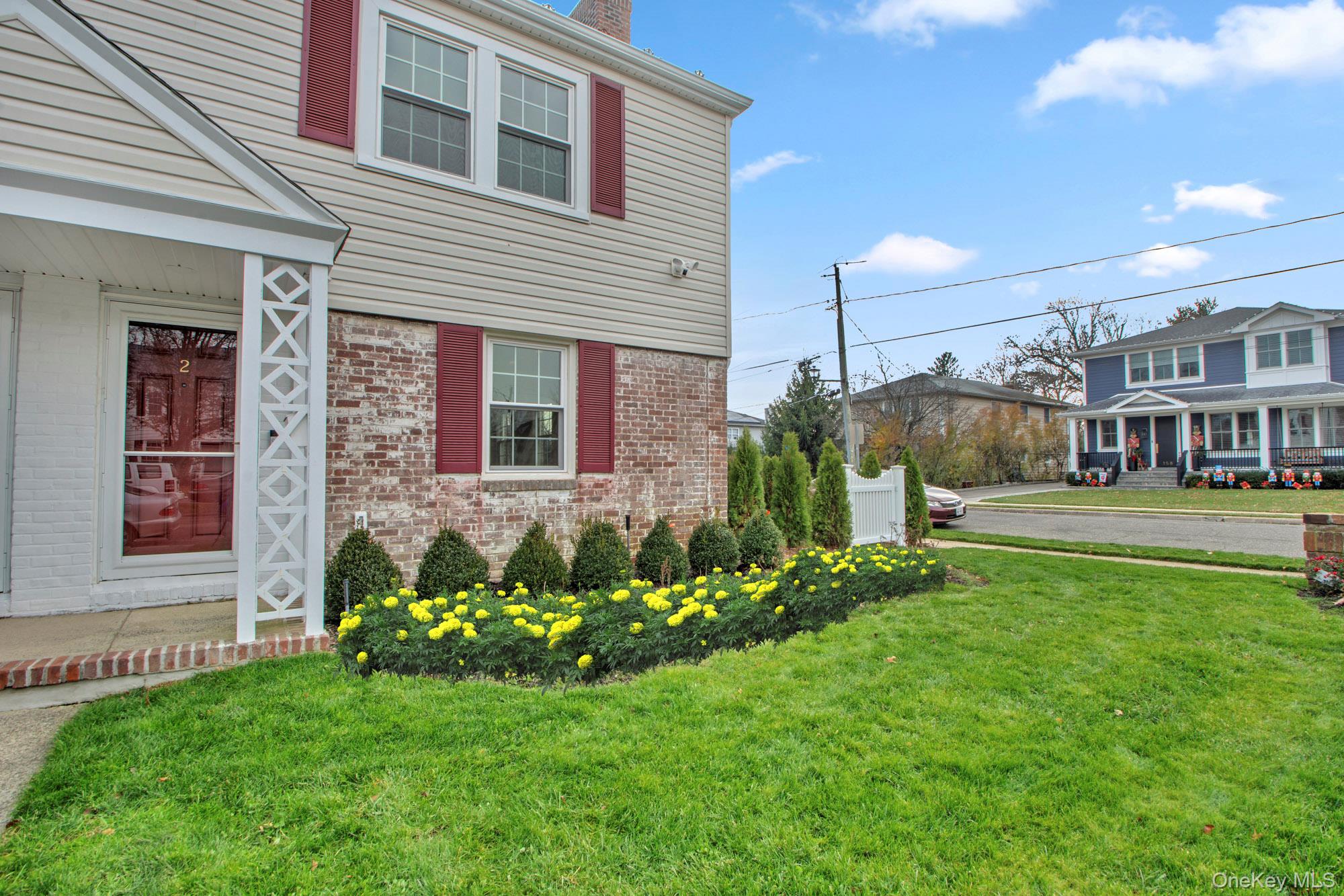 2 Bayview Court Manhasset, NY 11030 - Photo 2 of 21 View of side of property with brick siding, a yard, and a chimney